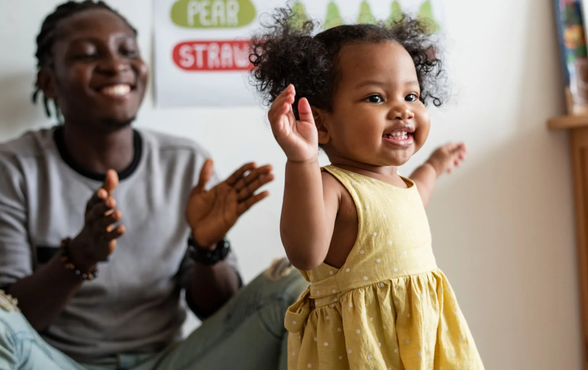 Bebê sorrindo e batendo palmas ao lado do pai