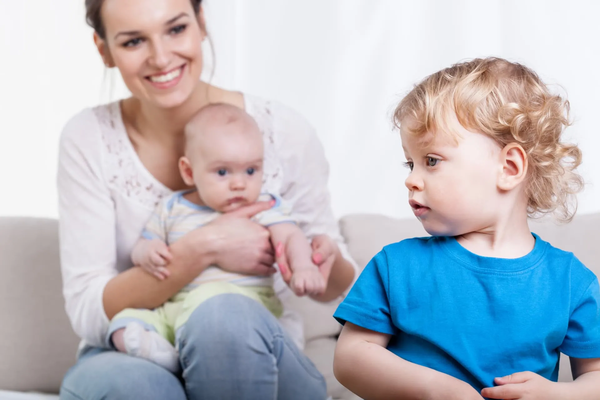 Mãe com bebê no colo ao lado de outra criança